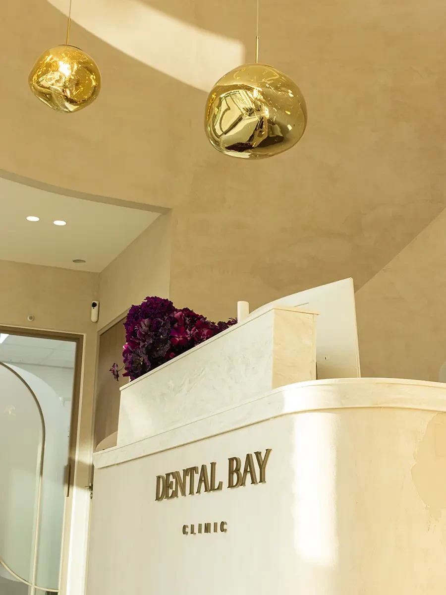 De ontvangstbalie van Dental Bay Clinic met gouden hanglampen